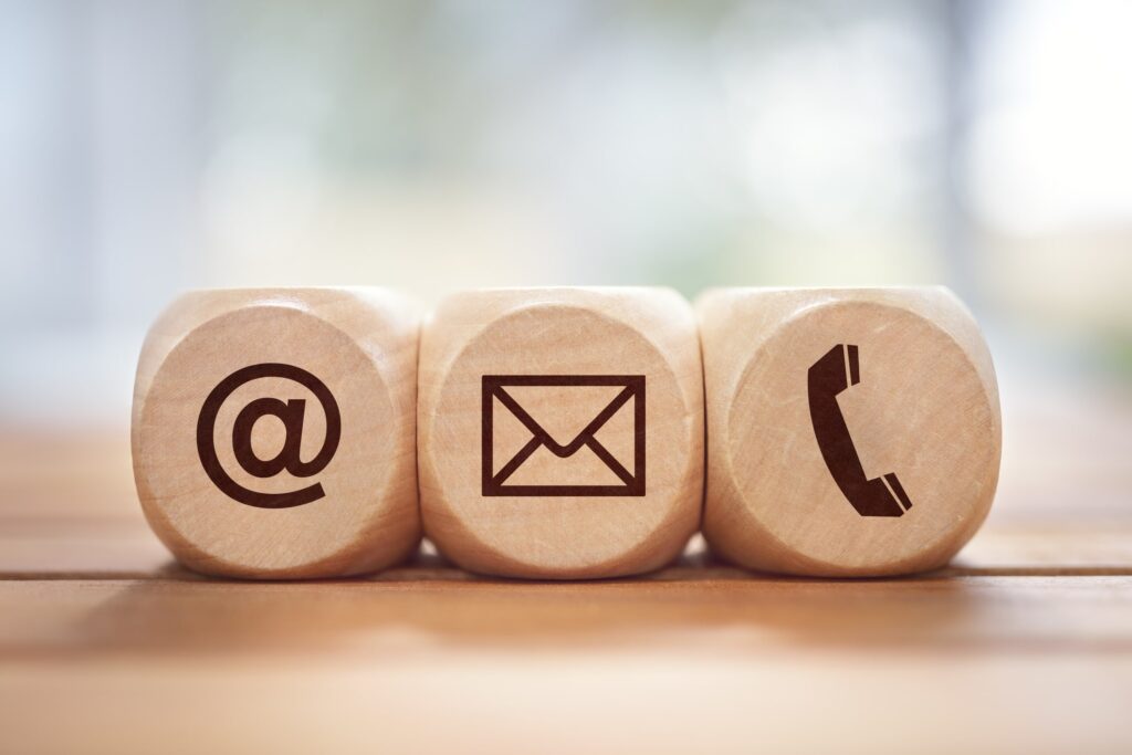 "Contact Us" concept with three wood blocks, each with a different symbol: one with @, one with an e-mail envelope, and one with a phone.
