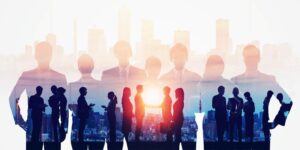 Groups of business people standing outside agree to a deal while the sun sets in the background.