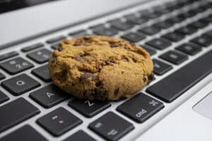 A chocolate chip cookie rests on a computer keyboard.