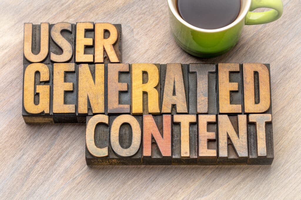 "User Generated Content" is presented as a word abstract in vintage, letterpress, wood-type blocks on a table beside a cup of coffee.