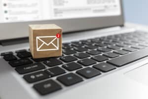 Email prospecting and deliverability concept: a cube with a new email icon rests on a laptop keyboard.