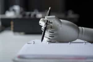 AI Digital Writing Assistant concept: a robotic hand holding a pen writes on a pad of paper.