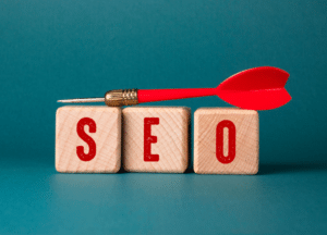 Blocks with red letters spell "SEO," while a red dart is balanced on top of them.