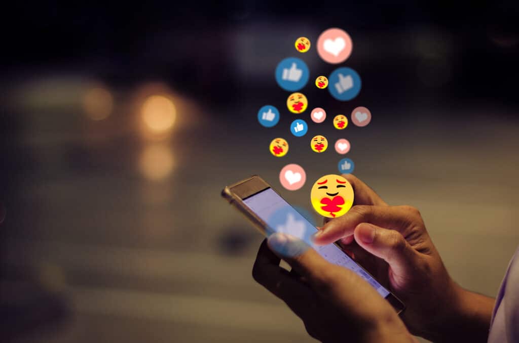 Social media reaction icons float above a smartphone.