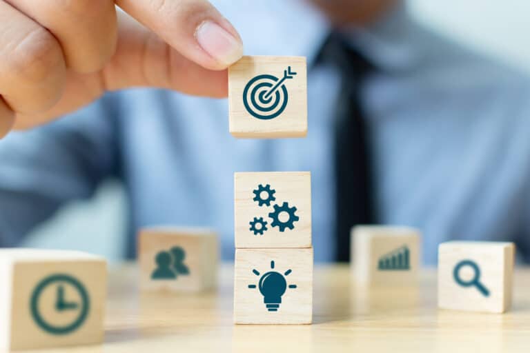 A Fractional CMO arranges a tower of blocks with icons representing marketing, from a bull's-eye and cogs to a lightbulb.