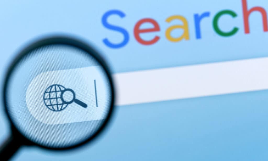 A magnifying glass hovers over an internet search bar on a web browser.