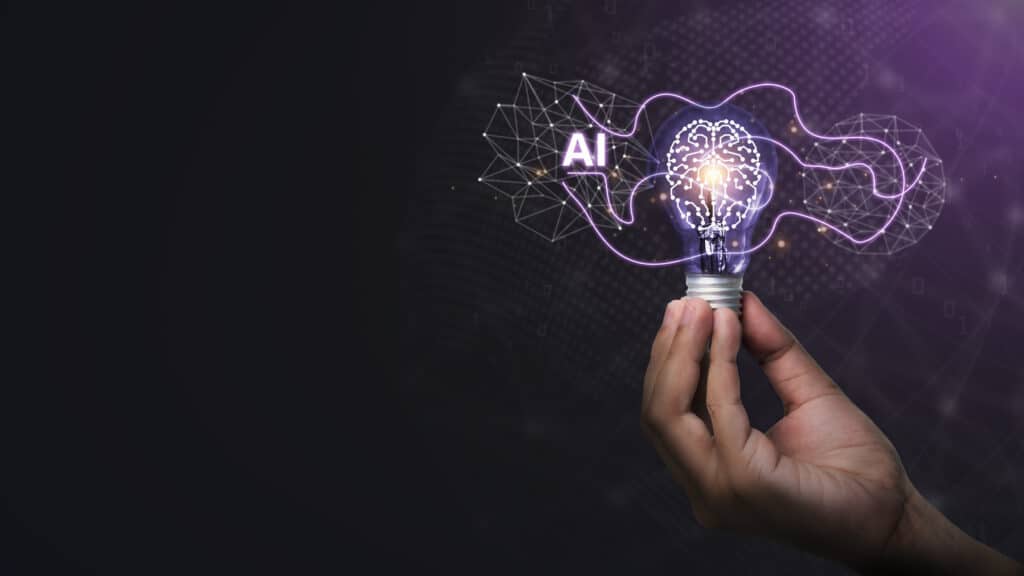 AI tools for SEO concept: a hand holds an illuminated lightbulb against a digital AI cloud. The lightbulb houses a digital brain made of circuit boards.